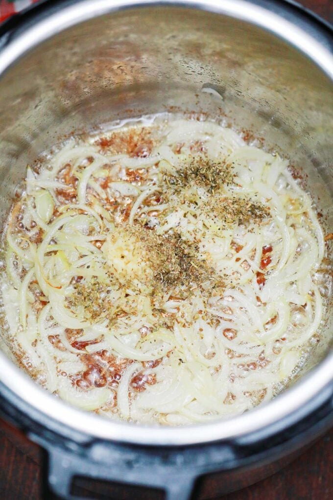 Sauteing onion, garlic, herbs, and spices in the instant pot.