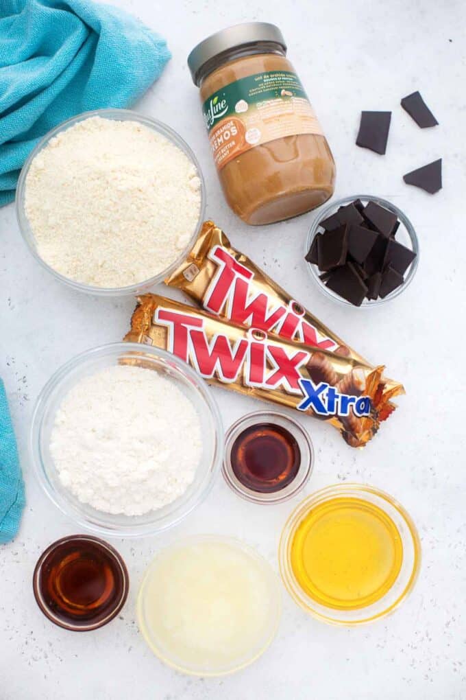 overhead shot of peanut butter twix bars ingredients arranged in bowls on a table