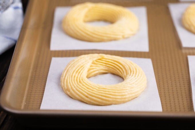 Piped Dunkin Donuts French cruller copycats on parchment paper.