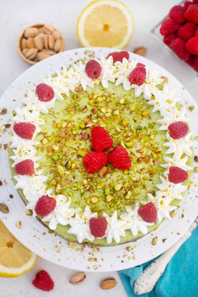 overhead shot of pistachio cheesecake with whipped cream raspberries and chopped pistachios