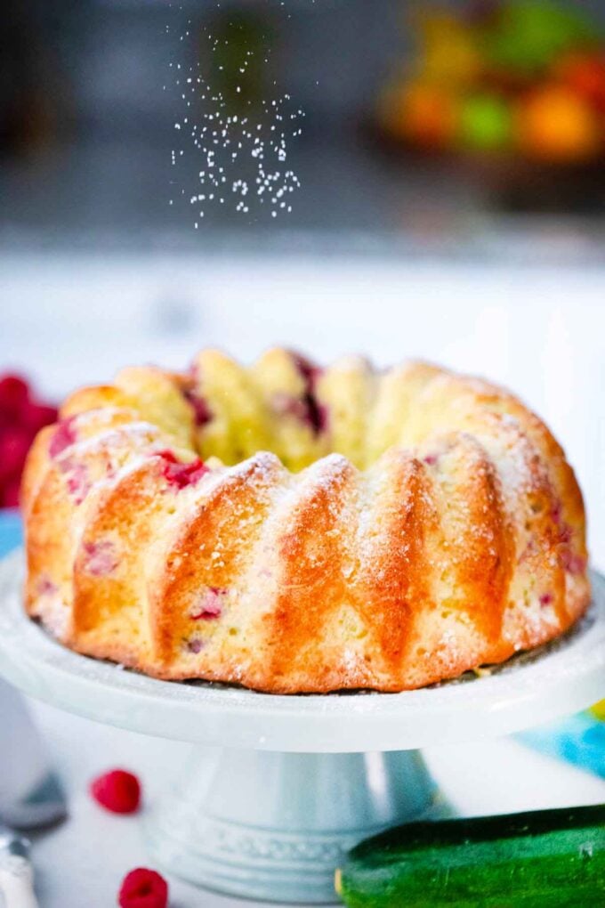sprinkling a raspberry zucchini bundt cake with powdered sugar