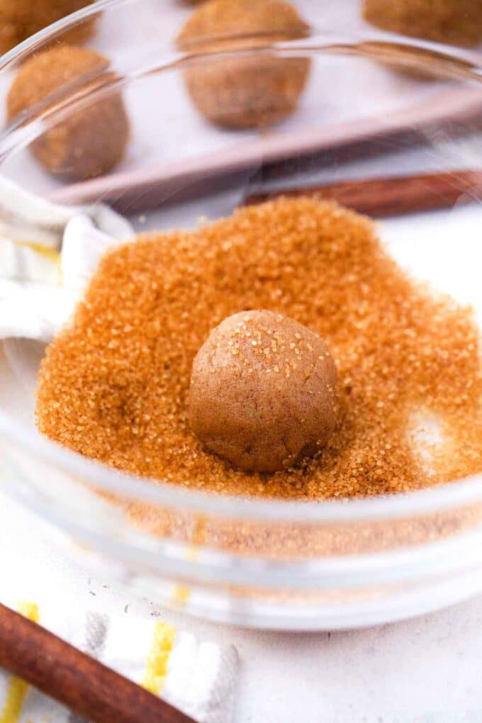 rolling molasses cookie dough ball in turbinado sugar