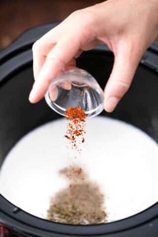 adding paprika to a creamy sauce in the slow cooker