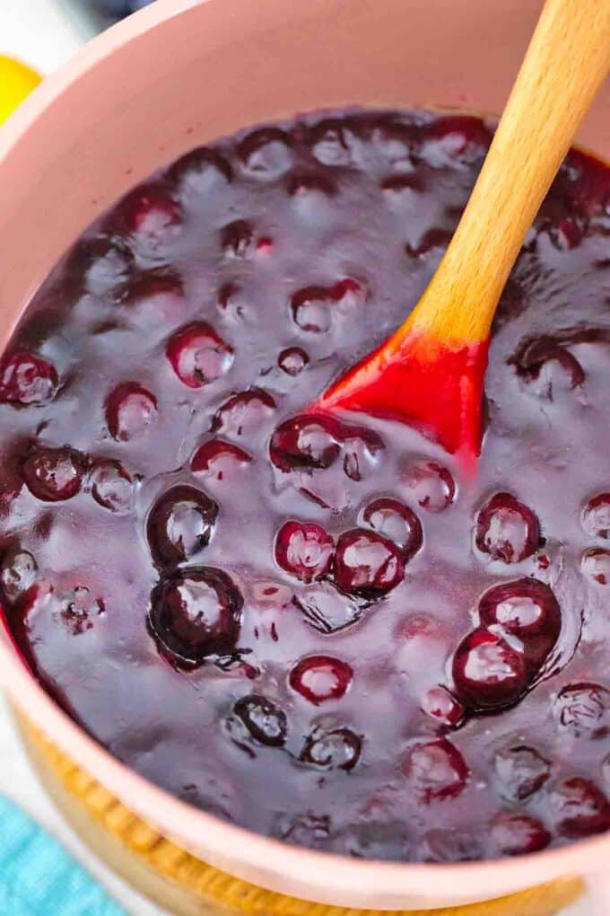 simmering blueberry pie filling into a small pink saucepan