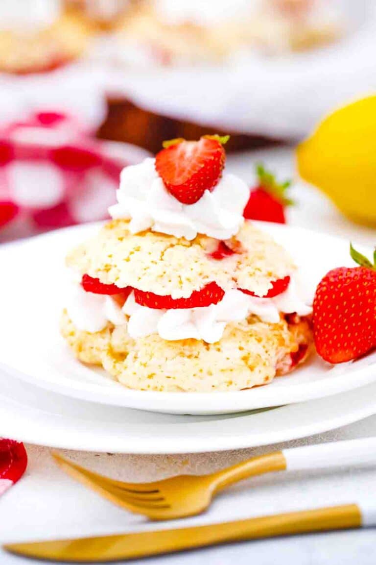 strawberry shortcakes on a white plate topped with whipped cream and fresh strawberries