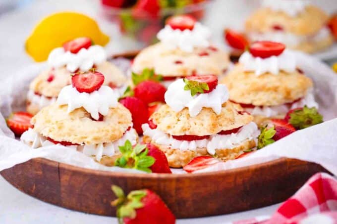 Strawberry shortcakes arranged on a wooden serving tray.