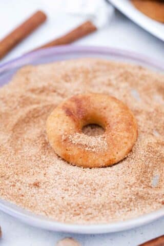 covering apple cider donuts in cinnamon sugar