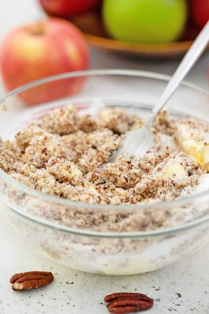 mixing apples with spices in a bowl