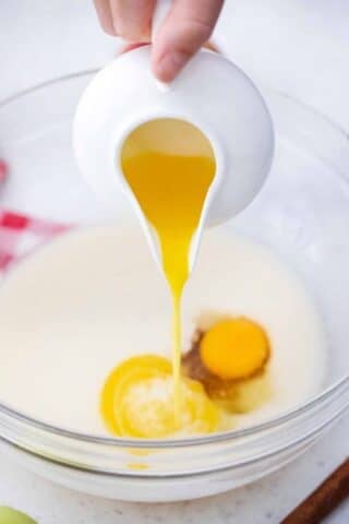 adding melted butter to a bowl with milk and egg
