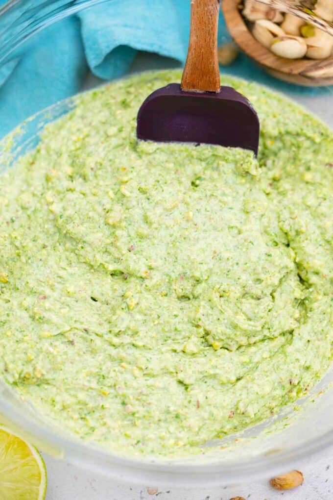 pistachio cake batter in a bowl with a spatula in it
