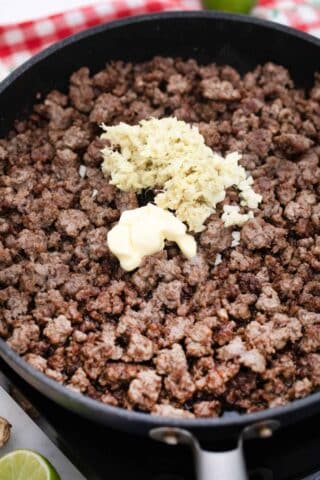 adding minced garlic and butter to ground beef