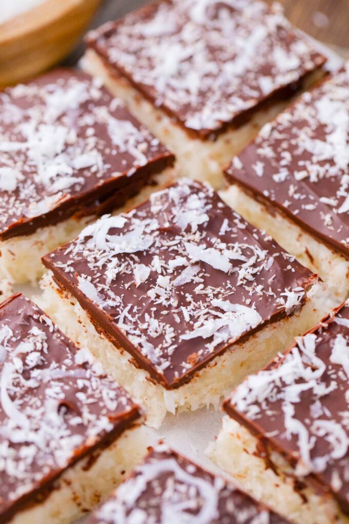 Chocolate coconut crack bars topped with shredded coconut flakes.