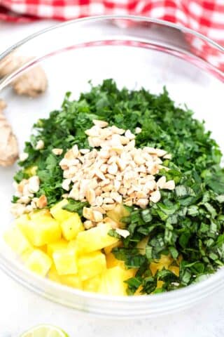 a bowl with pineapple chunks peanuts and chopped cilantro