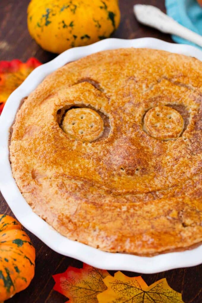 baked halloween apple pie topped with a scary face made out of crust