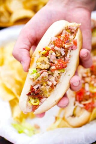 close shot of a man hand holding the holding viral chopped italian sandwich