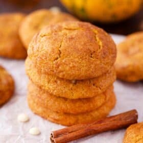 a stack of four pumpkin snickerdoodle cookies with cinnamon sticks next to them