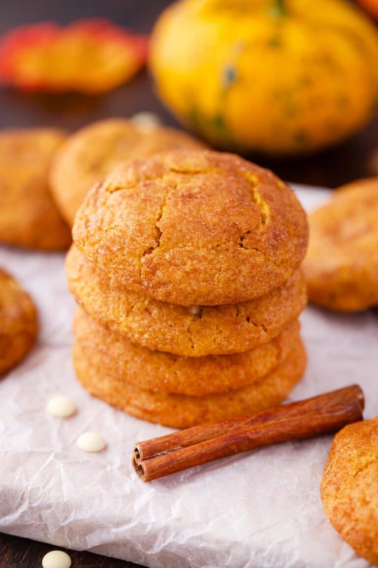 a stack of four pumpkin snickerdoodle cookies with cinnamon sticks next to them