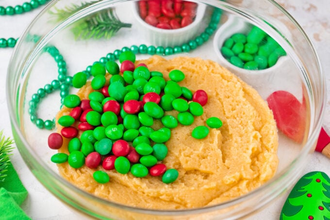 Adding red and greed M&M's to cookie bars dough.