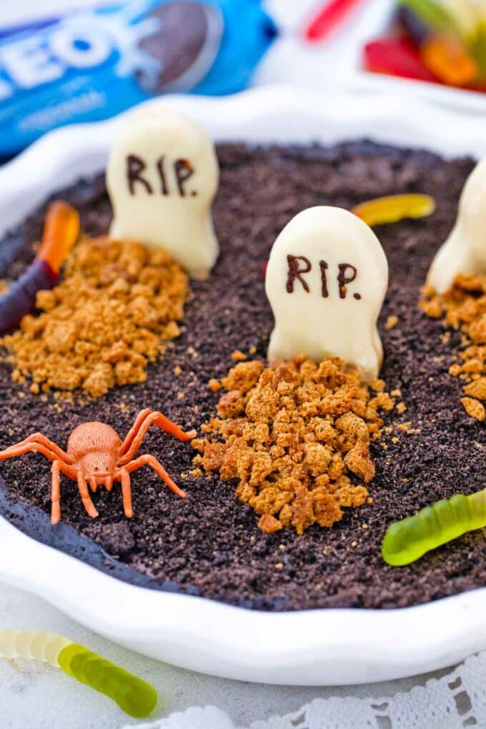 oreo dirt pie decorated for halloween with graved rip cookies worms and a spider