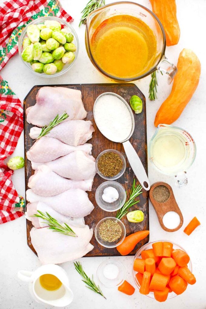 chicken legs and shoulders on a cutting board with spiced in bowl and veggies next to them