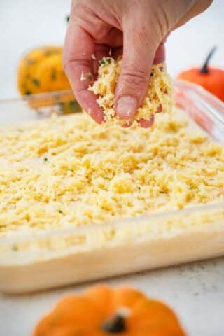 sprinkling cheese on top of a casserole dish