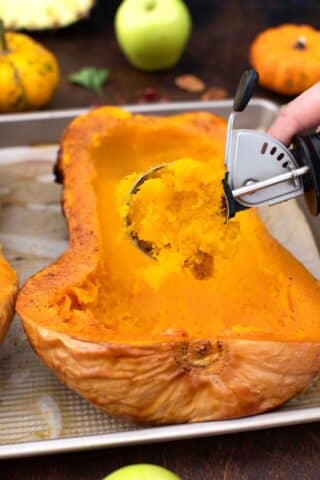 scooping the flesh of a baked butternut squash