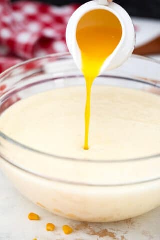 pouring melted butter into a bowl with a batter mixture