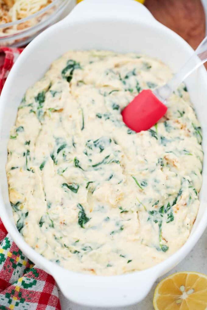 adding a layer of creamy spinach to a casserole dish