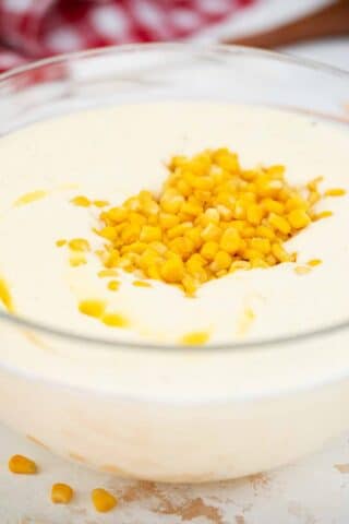 kernel corn on top of a corn pudding butter mixture in a bowl