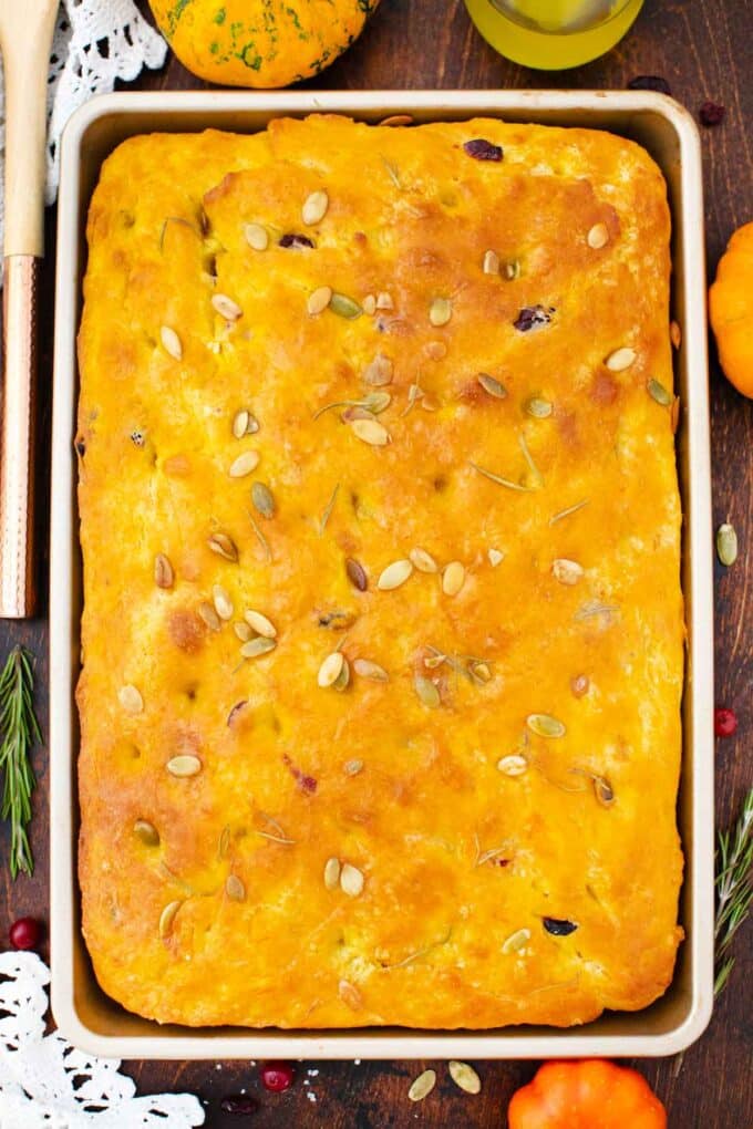 overhead shot of a baking sheet with cranberry pumpkin focaccia topped with rosemary