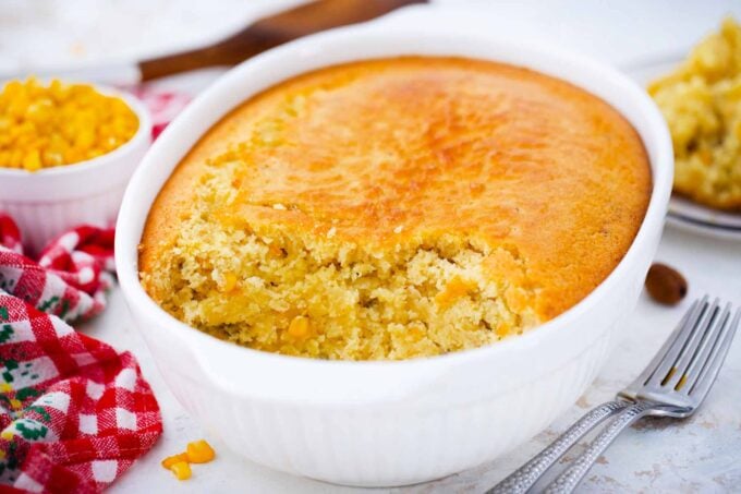 corn pudding casserole with some scooped from the sides, revealing its creamy interior