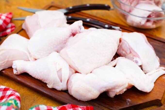 chicken cut into pieces on a cutting board with kitchen scissors in the background