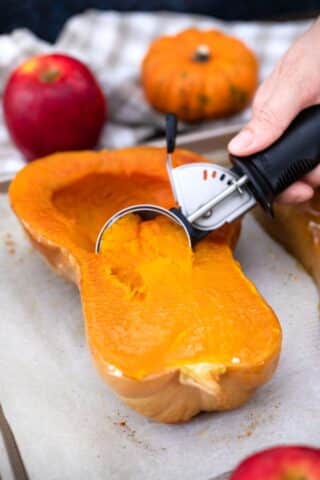 scooping the flesh of a cooked butternut squash