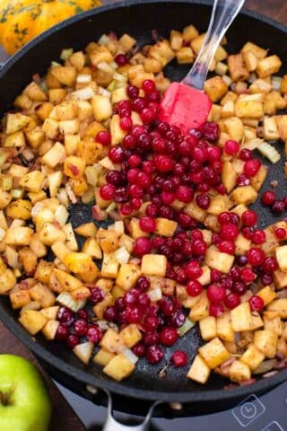 cooking chopped apples and cranberries in a skillet