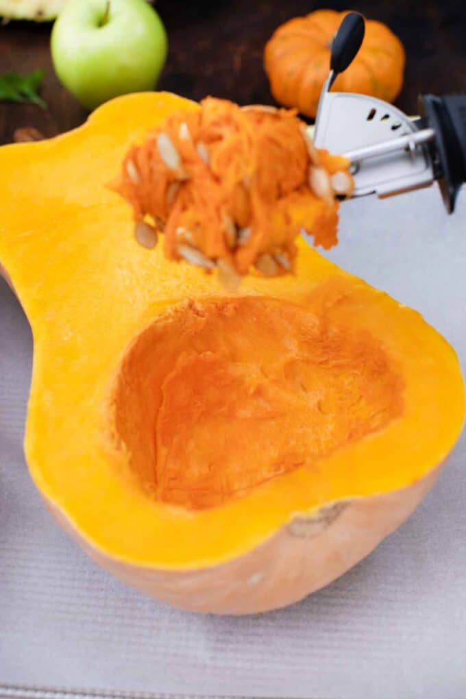 scooping the veins and seeds of a raw butternut squash
