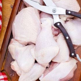overhead shot of a whole chicken cut into pieces on a cutting board with kitchen scissors on top