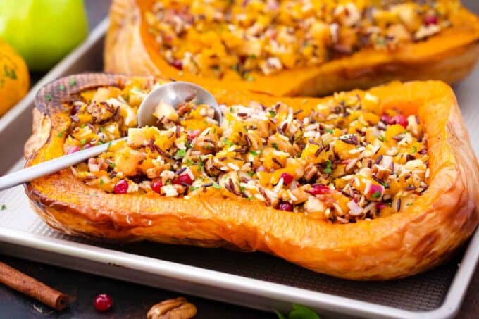 horizontal show of stuffed butternut squash arranged on a baking sheet with a spoon placed in the filling