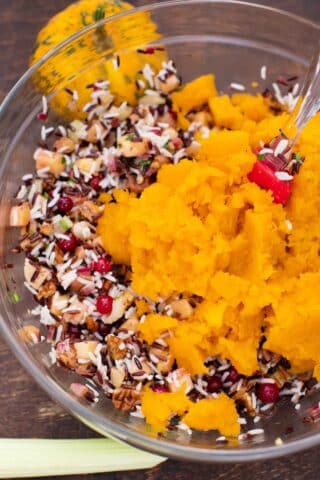 mixing butternut squash puree into a bowl with rice and other filling ingredients