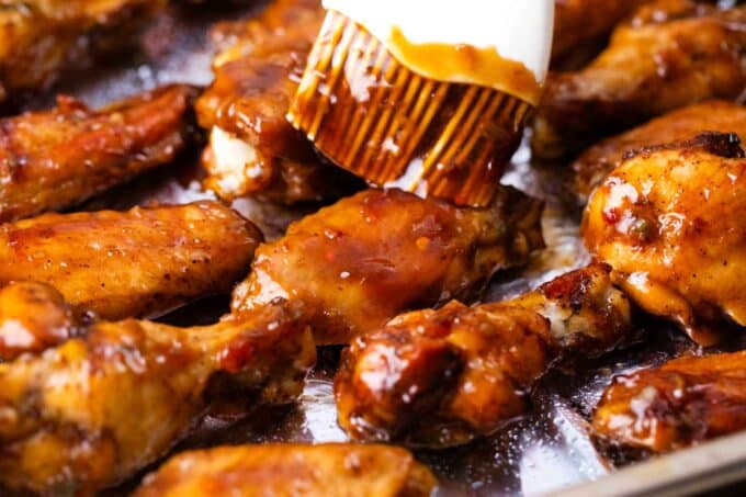 brushing honey garlic chicken wings with sauce