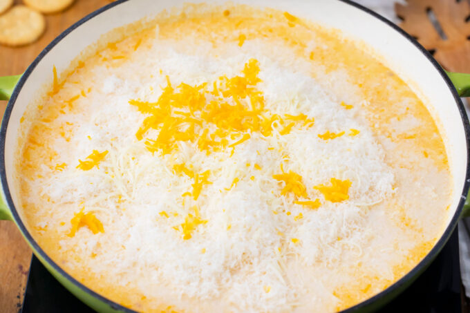 Adding grated cheese into sauce.