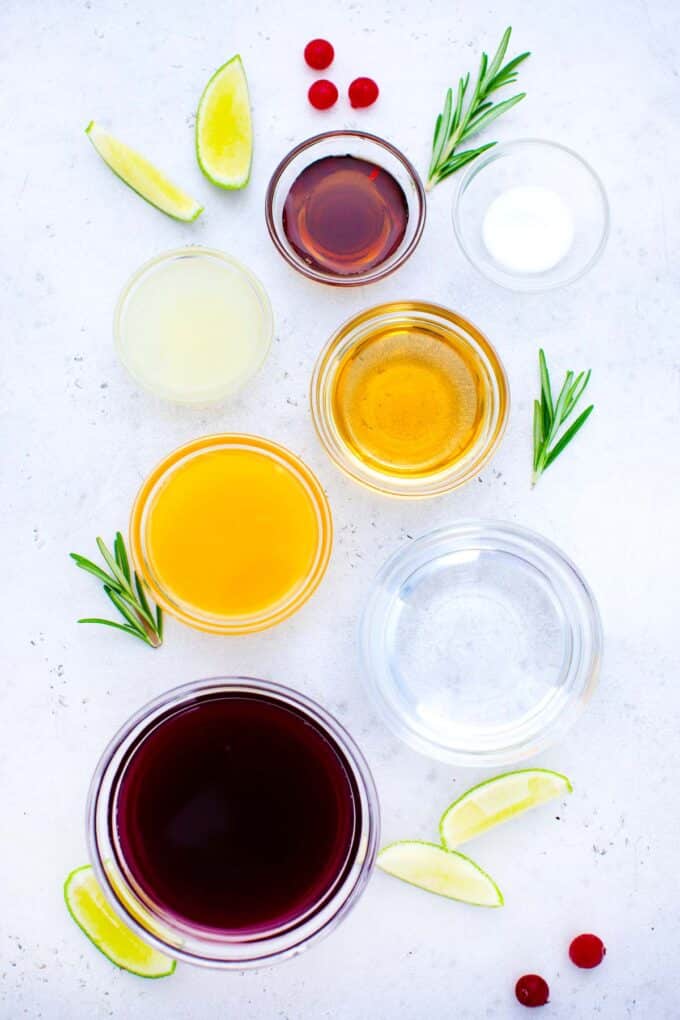 overhead shot of cranberry margarita ingredients in bowls arranged on a white table