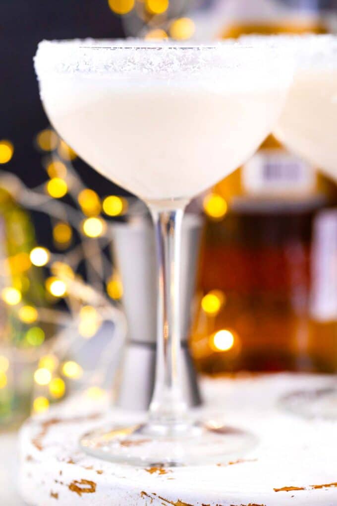 a glass of creamy snowflake martini with Christmas lights in the background