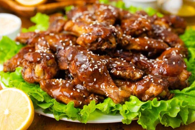 oven baked honey garlic chicken wings on a plate with salad leaves