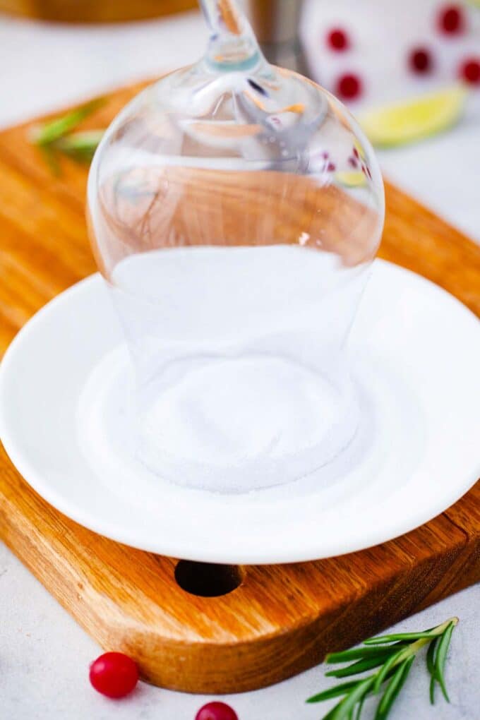 dipping a cocktail glass in salt to make a salt rim