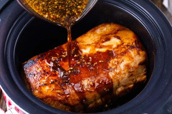 Adding balsamic sauce to pork loin in the crockpot.