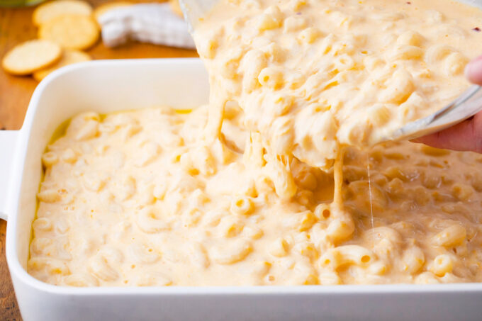 Pouring gluten free mac and cheese into a baking dish.
