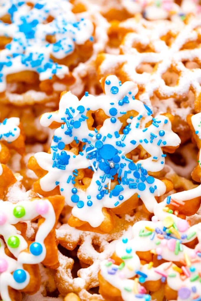 crispy rosette cookies shaped like snowflakes and topped with icing and blue sprinkles