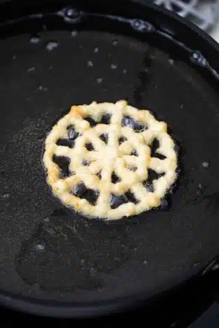 frying a rosette snowflake shaped cookie