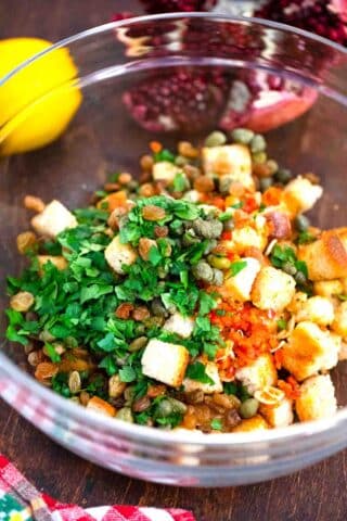 mixing croutons with capers and parsley in a bowl