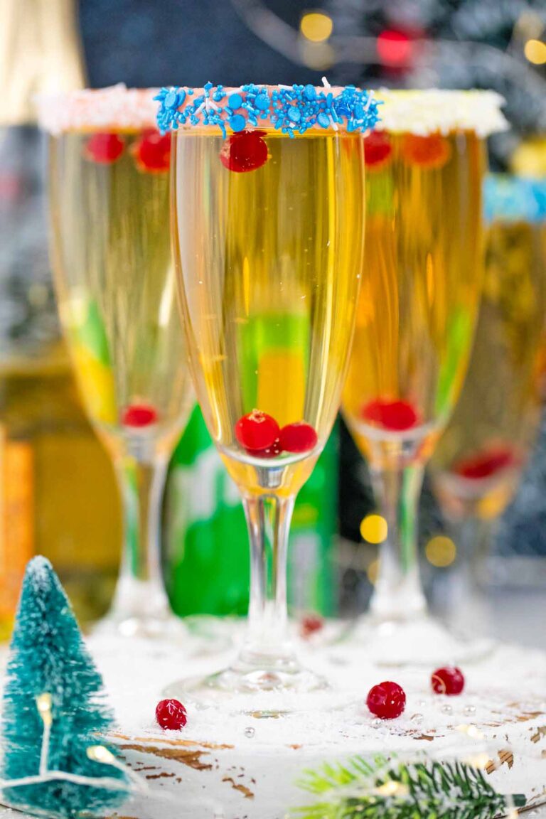 new year festive champage cocktail with buttercream sprinkle rim with Christmas decor in the background